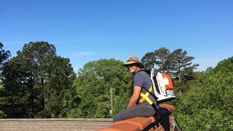 Aaron's technician astride a brick chimney with a backpack blower unit